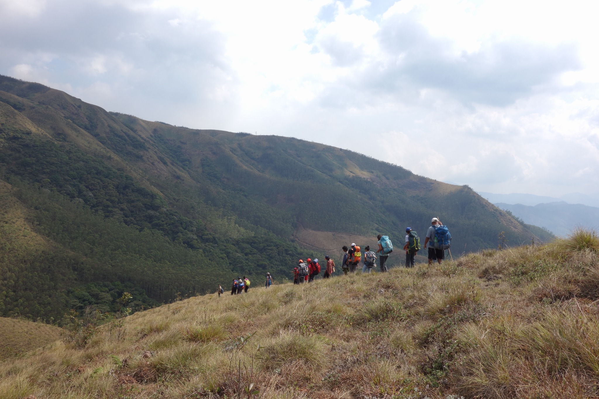 Group of backpackers walking along a ridge line with deep valley view