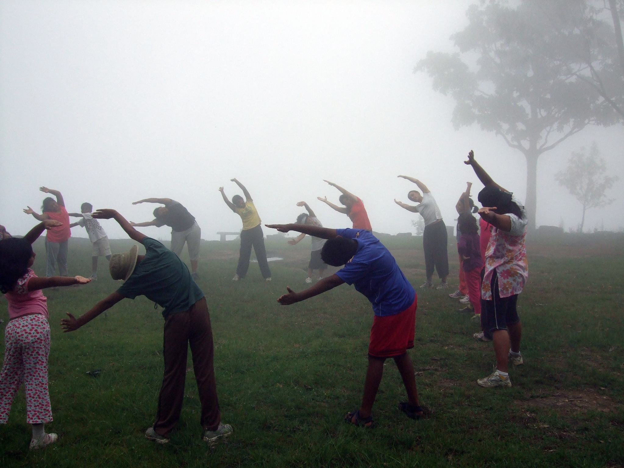 Group performing morning stretches in misty high altitude mountains