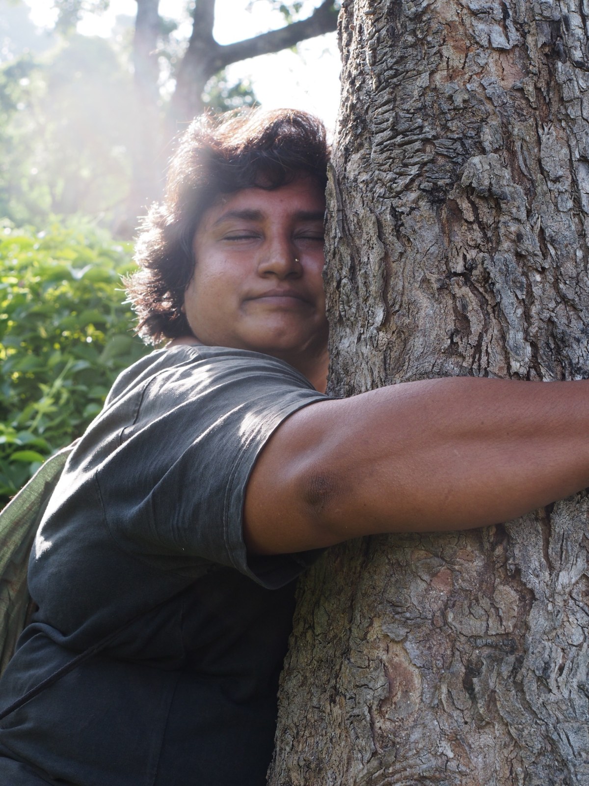 Daya embracing a tree in the forest