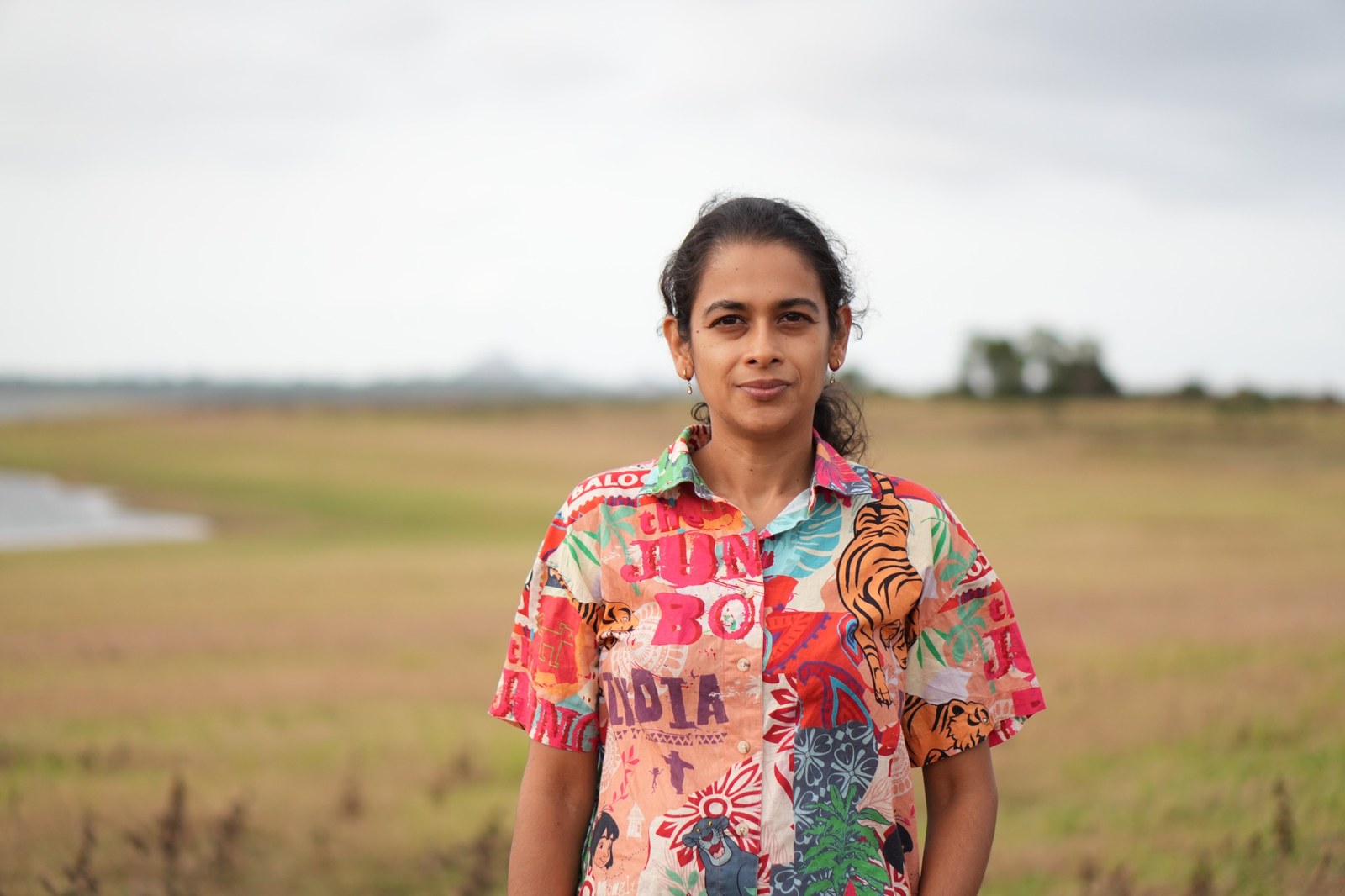 Divya standing outdoors in a field