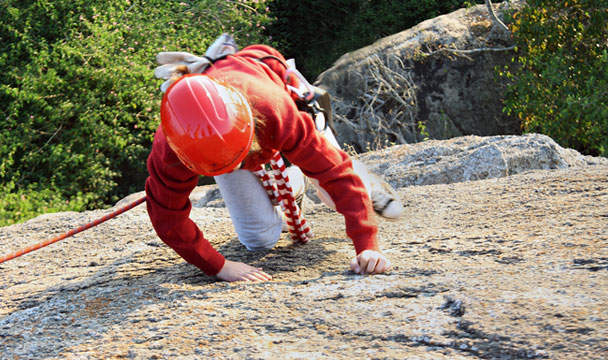 Climber working their way up a rock face, hands and feet gripping the granite